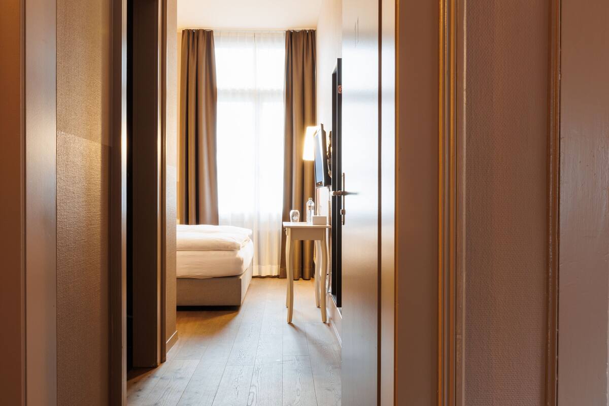A hotel room with a bed, a desk, and a television.