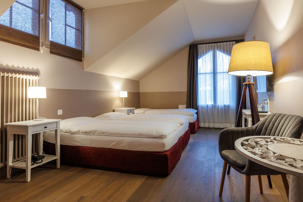 A hotel room with a bed, bedside tables, a desk, a chair, and a lamp.