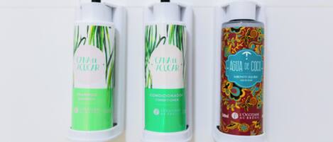 Three bottles of shampoo, conditioner, and soap arranged on a white surface.