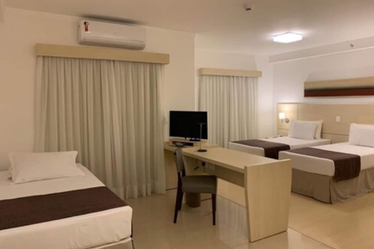 Une chambre d’hôtel avec deux lits, un bureau avec un ordinateur et une télévision.
