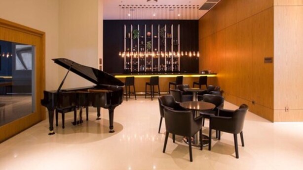 Een modern interieur met een vleugelpiano, ronde tafels en een bar.