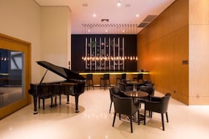Un interior moderno con un piano de cola, mesas redondas y una zona de bar.