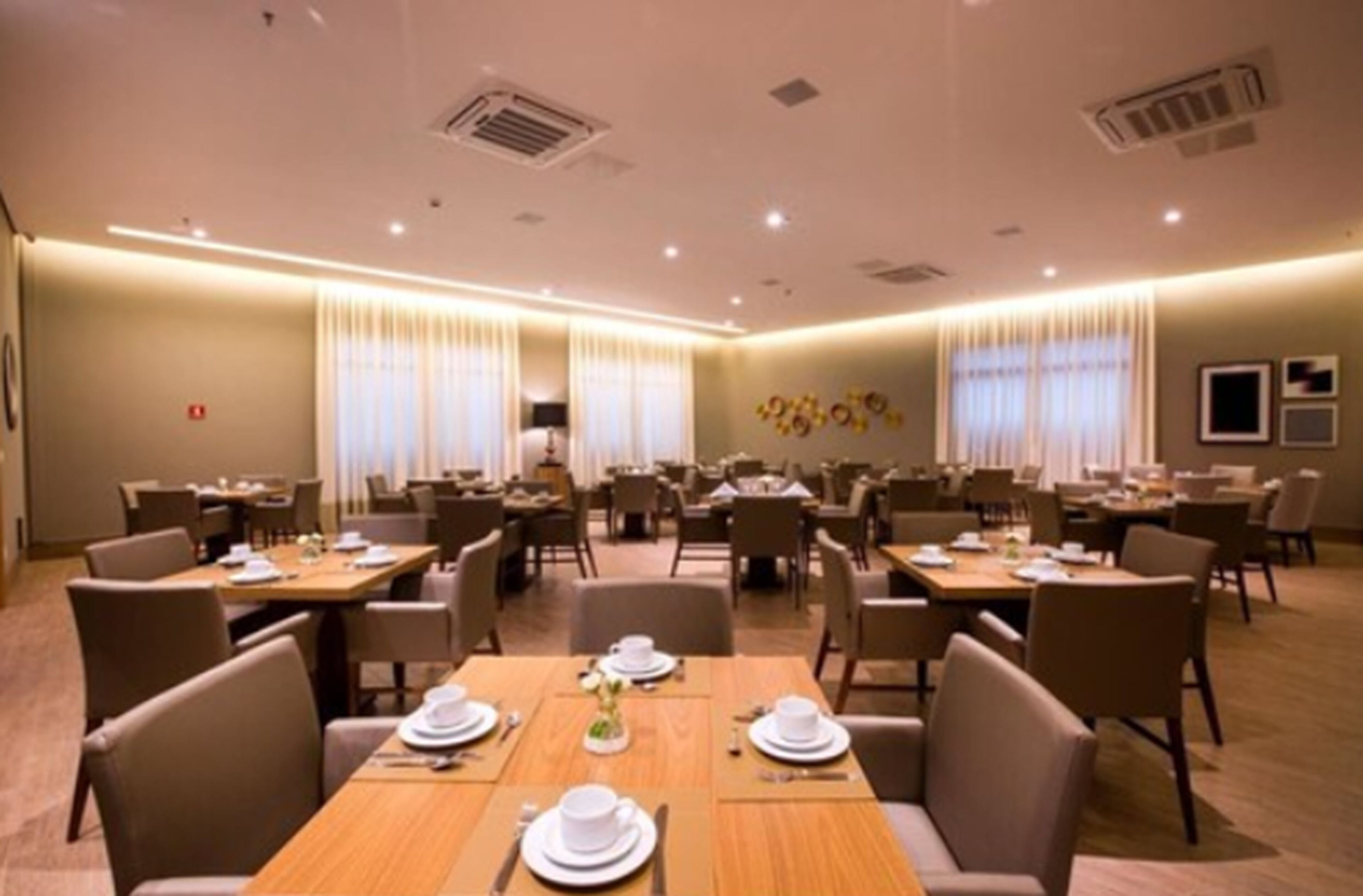 A hotel dining area with multiple tables and chairs, arranged in a spacious layout.