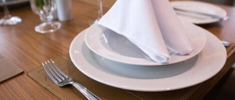 A neatly set dining table with a folded napkin, a fork, and a glass of water.
