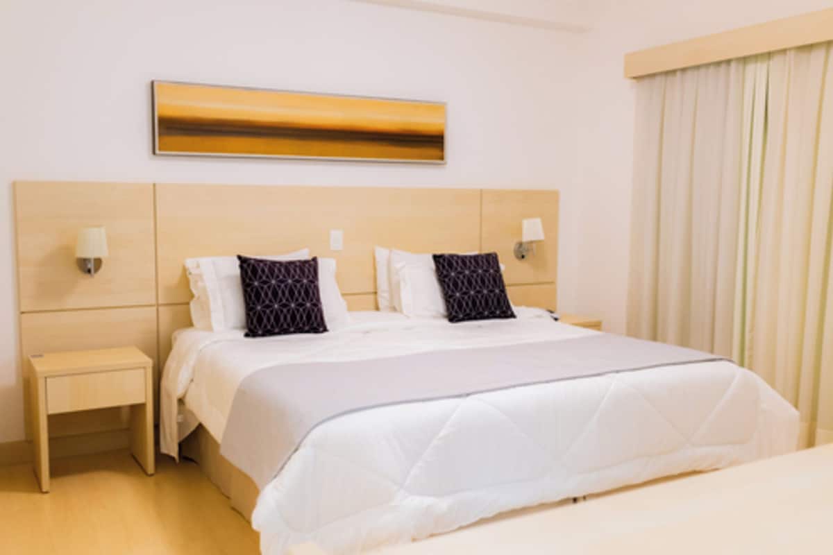 Une chambre d’hôtel avec un grand lit, deux tables de chevet et une œuvre d’art accrochée au mur.