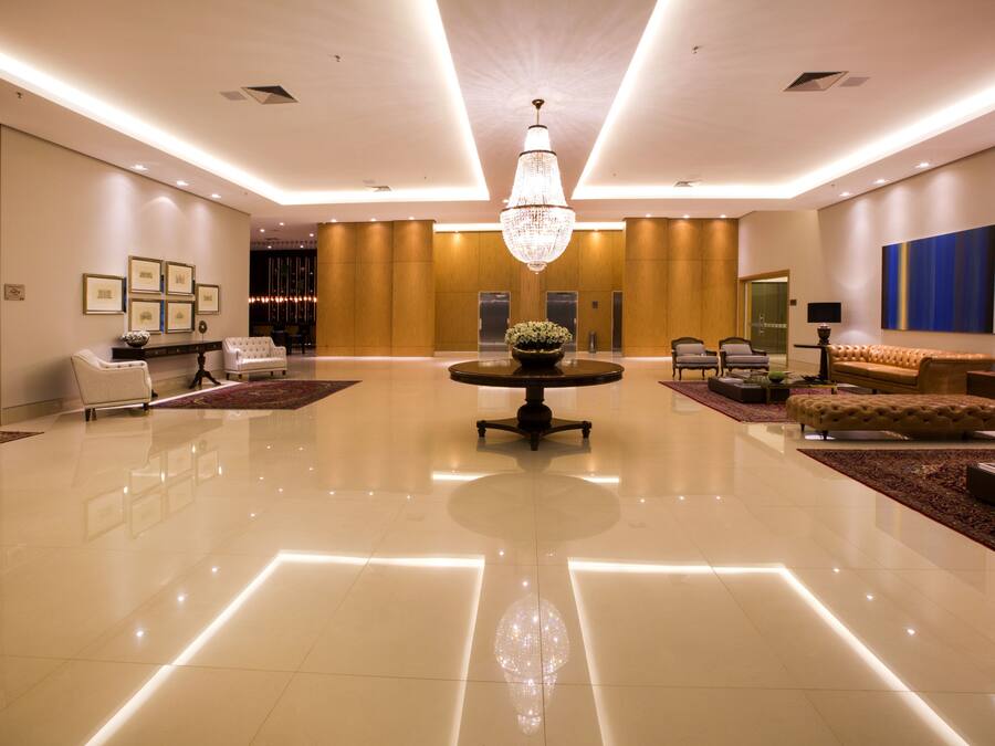 Eine geräumige Lobby mit einem runden Tisch in der Mitte, einer Chandelüster und einer Sitzecke mit Sofa und Sesseln.