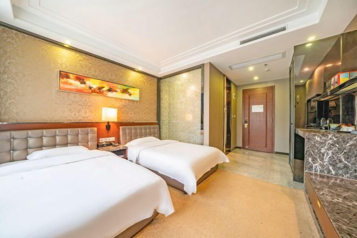 A hotel room with two beds, a marble bathroom, and a view of the city.