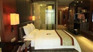 A hotel room with a large bed, a desk, a chair, a TV, and a minibar. - Enping Jinzhou Holiday Hotel (Jiangmen)
