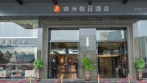 A hotel entrance with a reception desk, potted plants, and a red carpet leading to the entrance. - Enping Jinzhou Holiday Hotel (Jiangmen)