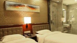A hotel room with two beds, a nightstand, a lamp, a painting, and a glass-enclosed shower area. - Enping Jinzhou Holiday Hotel (Jiangmen)