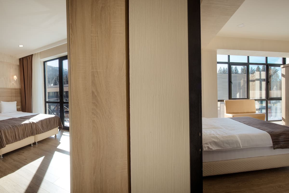 A modern hotel room with two beds, a large window, and a view of a mountain.