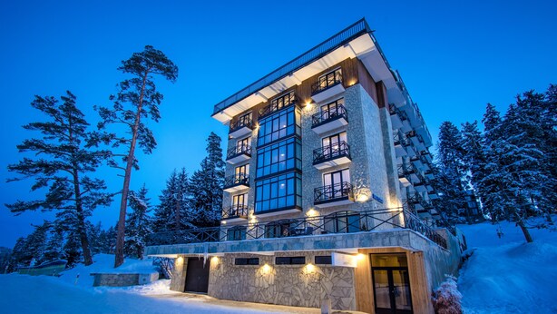 A multi-story hotel with a stone facade, large windows, and balconies. - BM Plaza (Borjomi)