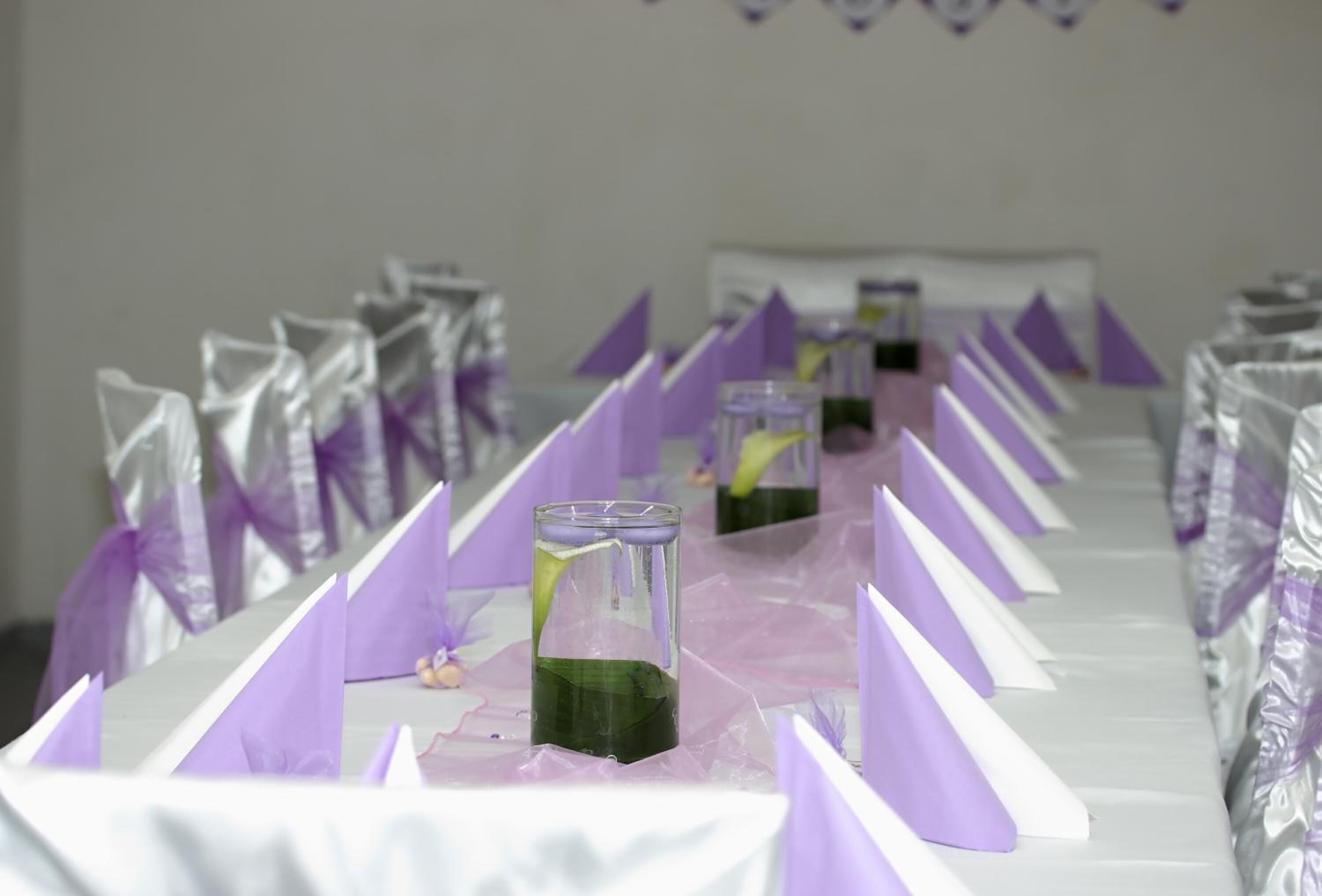 Un lungo tavolo con decorazioni viola e bianche, probabilmente allestito per un'occasione speciale.