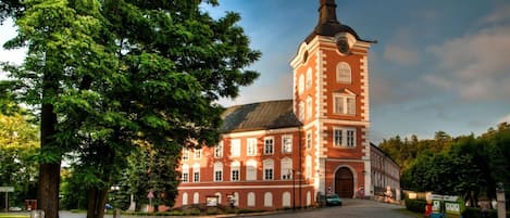 Un edificio histórico de ladrillo rojo con una torre destacada y ventanas de arco.