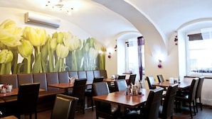 En restaurang med avskilda bås och bord, en stor väggmålning med blommotiv och en luftkonditioneringsanläggning.
