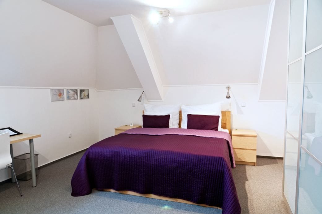 Un dormitorio con cama, mesitas de noche, escritorio y silla.