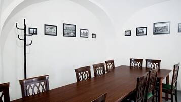A conference room with a long wooden table, six chairs, and a coat rack.