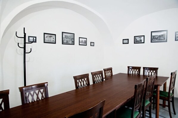 A conference room with a long wooden table, six chairs, and a coat rack. - Hotel Berger (Kamenice nad Lipou)