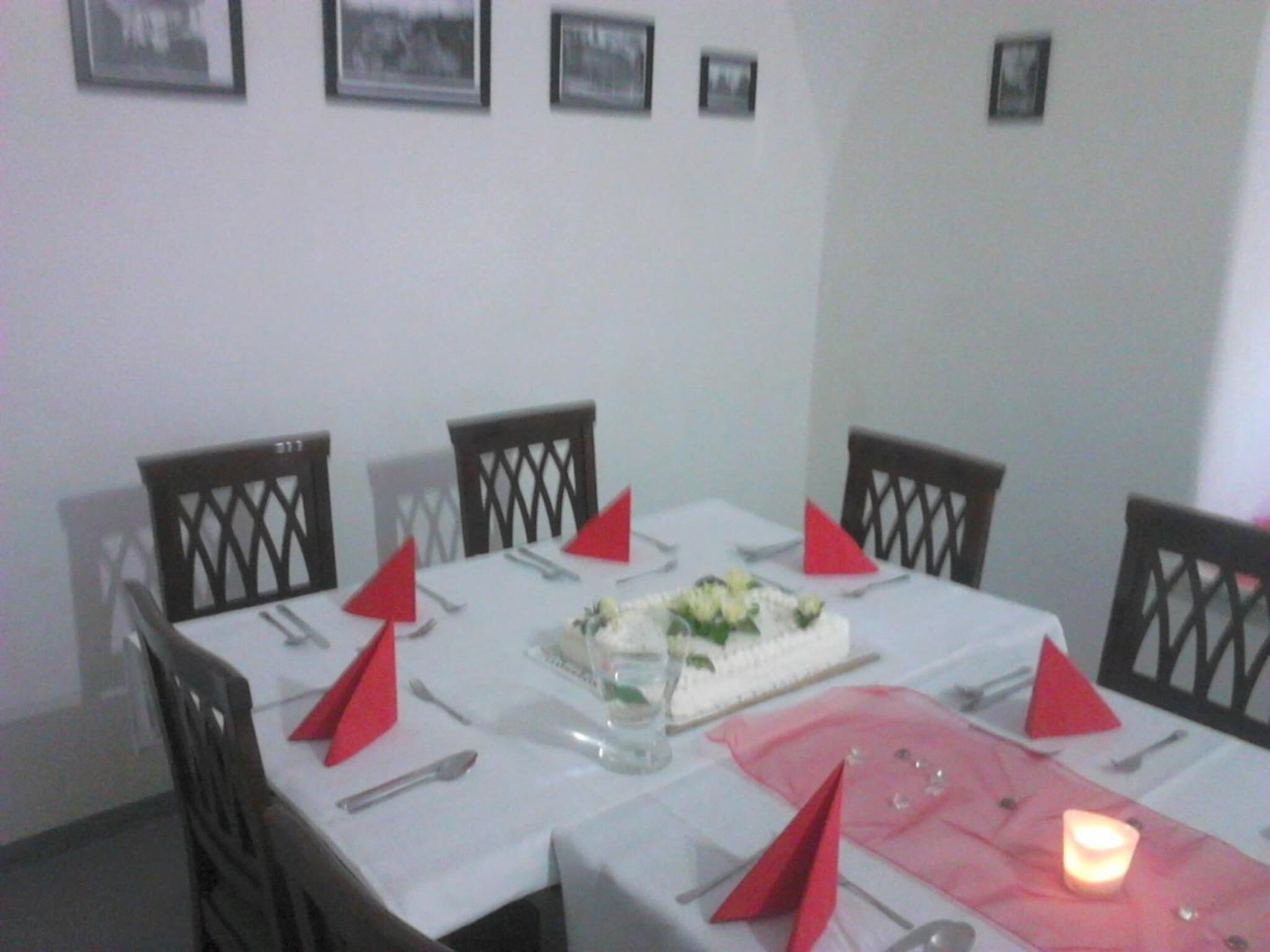 Un comedor con una mesa blanca, servilletas rojas y un pastel sobre la mesa.
