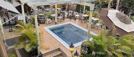 Área de piscina en la azotea con una pérgola, asientos y escalones que bajan a la piscina.