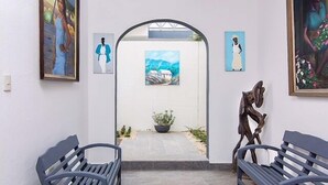 Een kunstgalerie met bankjes, schilderijen en een sculptuur.
