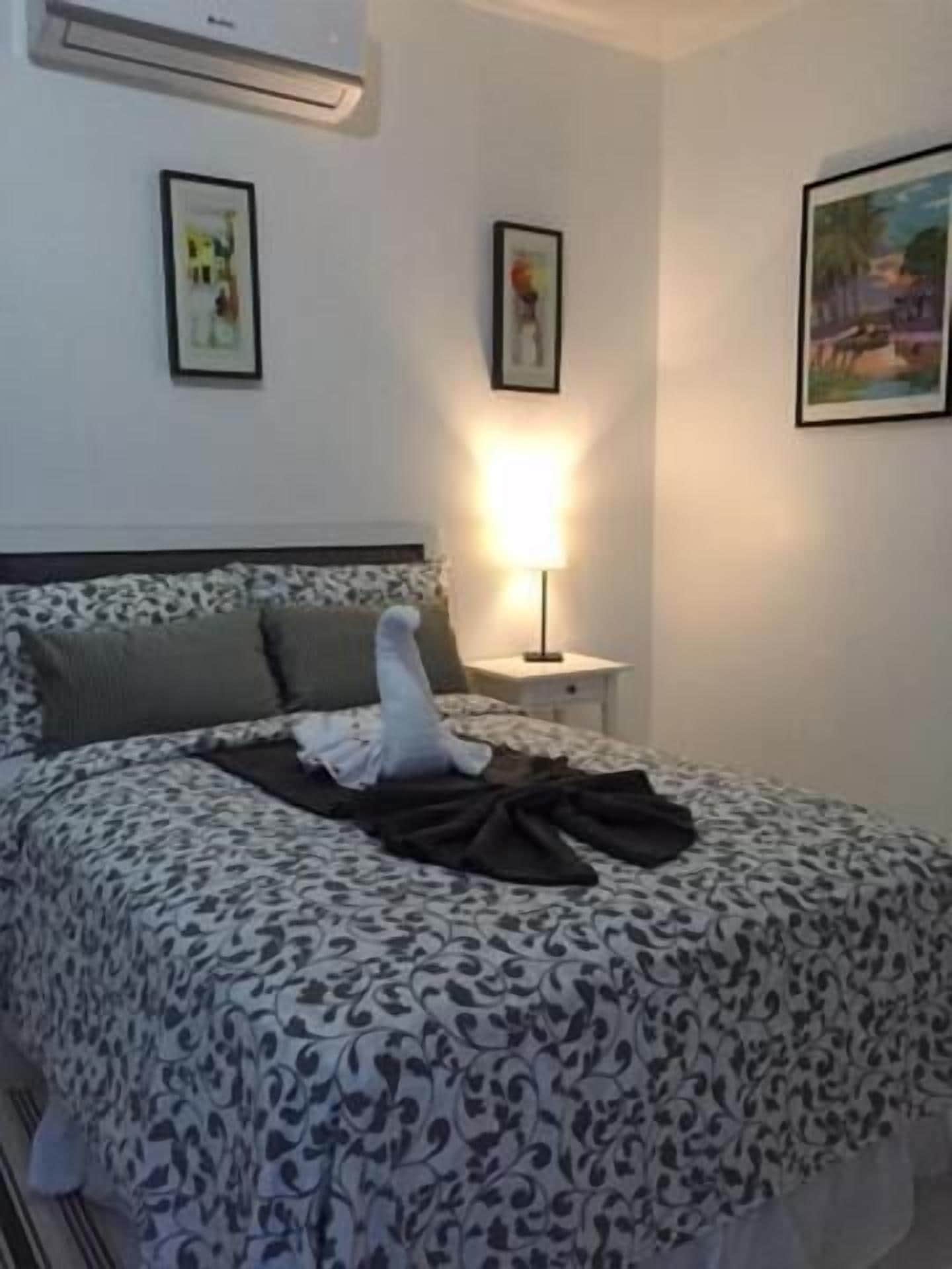 A bedroom with a bed, a bedside lamp, and framed pictures on the wall.