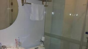 A bathroom with a white sink, toilet, and glass shower enclosure. - Hanting Hotel (Shaoxing)