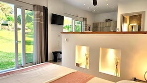A modern hotel room with a large bed, a ceiling fan, a TV, and a view of the outdoors. - Villa Claire Corfu (Corfu)