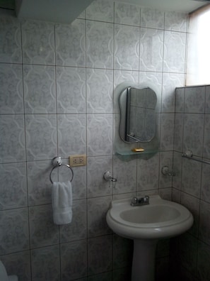 A bathroom with patterned tiles, a glass-topped sink, and a towel rack.