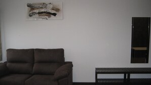 A room with a brown sofa, a wooden bench, and a framed abstract artwork on the wall. - Suites A Coruña (A Coruña)