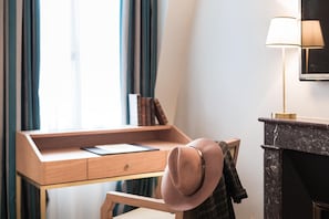 A room with a desk, a chair, a hat, a lamp, and a fireplace. - Hotel Alfred Sommier (Paris)