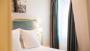 Una habitación de hotel con una cama, una mesita de noche, una lámpara y cortinas.