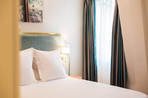 A hotel room with a bed, a nightstand, a lamp, and curtains. - Hotel Alfred Sommier (Paris)