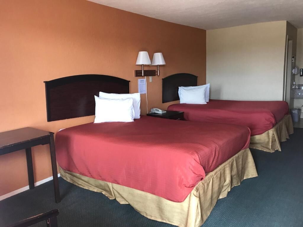 A hotel room with two beds, a desk, and a telephone.