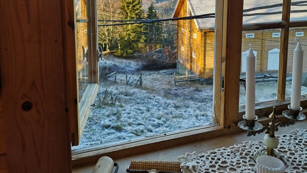 A wooden window with a view of a snowy landscape and a wooden house. - Haugtun gårdspensjonat og kulturverksted (Nordre Land)
