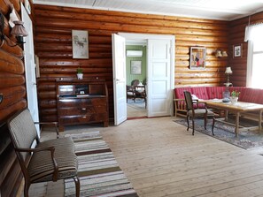 Ein Blockhaus-Interieur mit einer hölzernen Bank, einem Holztisch, einer roten gepolsterten Bank und einem Holzschrank.