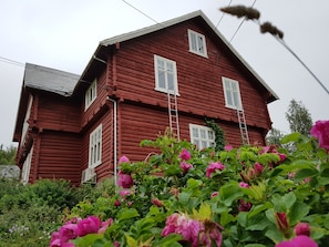 A red wooden house with white windows and a sloped roof.