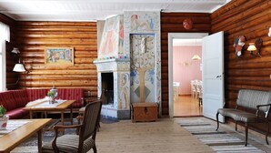 A cozy log cabin interior with a fireplace, wooden walls, and a dining area. - Haugtun gårdspensjonat og kulturverksted (Nordre Land)