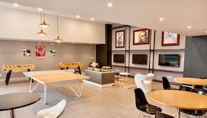 A modern lounge area with a foosball table, ping pong table, and comfortable seating. - Moon Luxury Apartments (Santiago de Surco)