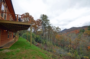 A wooden cabin with a covered porch and a view of a forested mountain. - Free Railroad Tix + Amazing patio w/ Fire Pit + Home Theater + Hot Tub Almost Heaven (Bryson City)