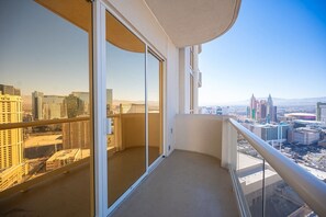 Ein Balkon mit Blick auf die Stadt, eine Glastür und ein Metallgeländer.