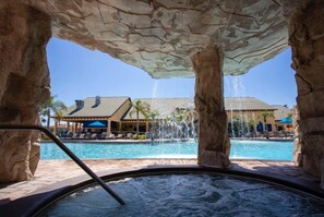 A hot tub area with a pool and a building in the background.