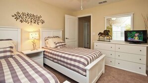 Camera da letto con due letti, una ventola a soffitto, una TV, un cavallo decorativo e una finestra con persiane.