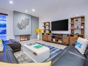 Een moderne woonkamer met een open haard, een flatscreen televisie en een boekenkast.