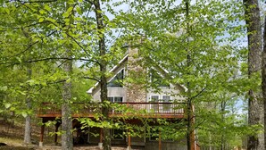 A cabin with a wooden deck and a stone foundation, surrounded by trees and a forested area. - Mountain/lake community in Poconos,PA (Lackawaxen)