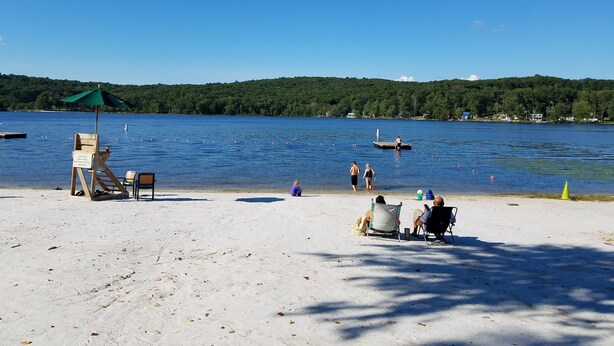 A beach with a lifeguard stand, a sandy shore, and a lake with boats and swimmers. - Mountain/lake community in Poconos,PA (Lackawaxen)