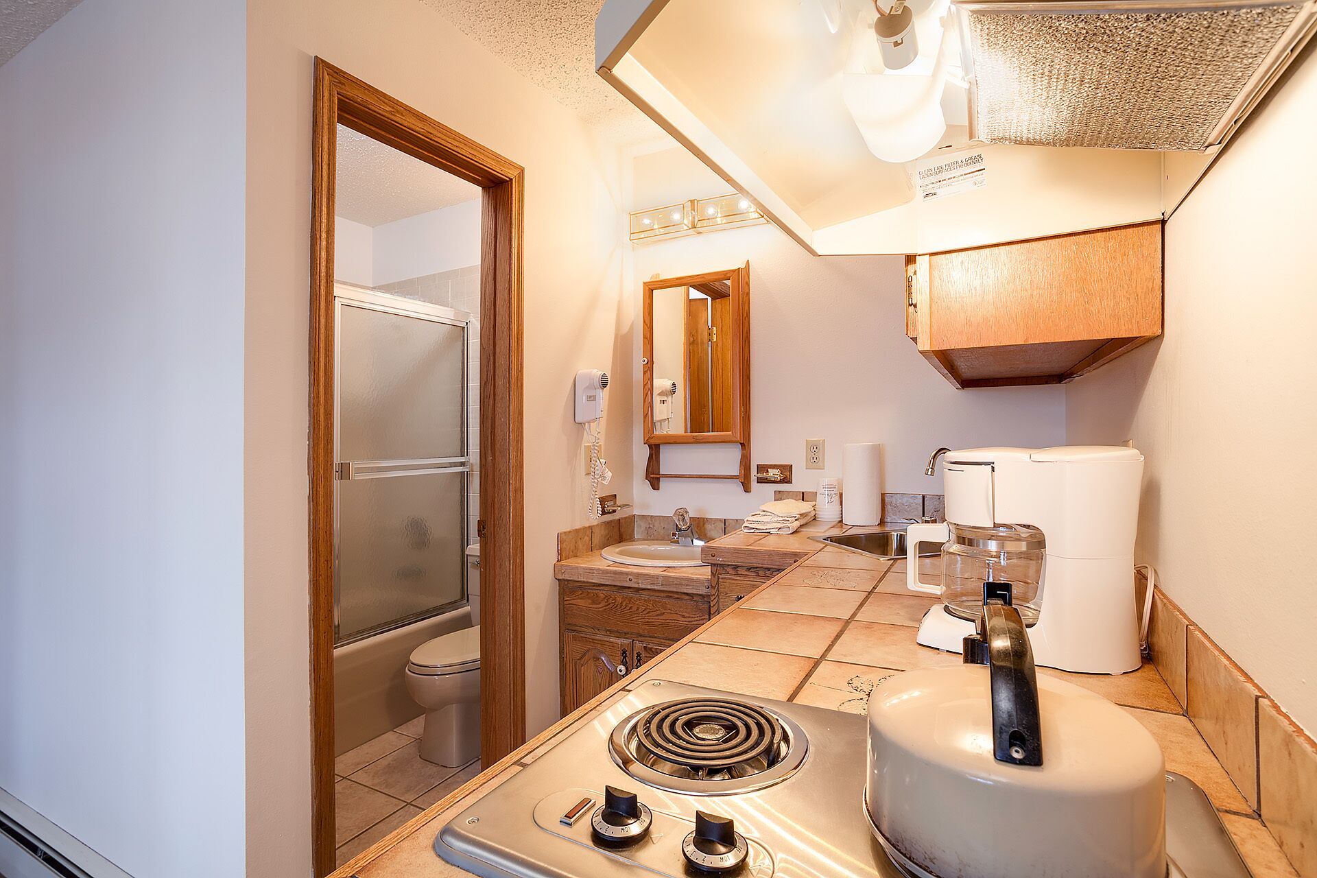 A bathroom with a shower, toilet, sink, and a stove.