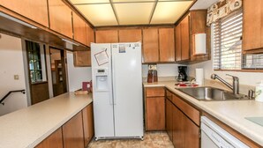A compact kitchen with wooden cabinets, a white refrigerator, a dishwasher, and a sink.