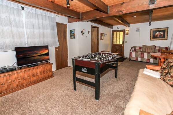 A cozy living room with a foosball table, a television, and a sofa.