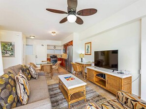 A living room with a sofa, coffee table, TV, and a dining area with chairs and a table. - Touch the Palms! Island-Style Condo w/Free WiFi, Full Kitchen–Waikīkī Shore #316 (HONOLULU)